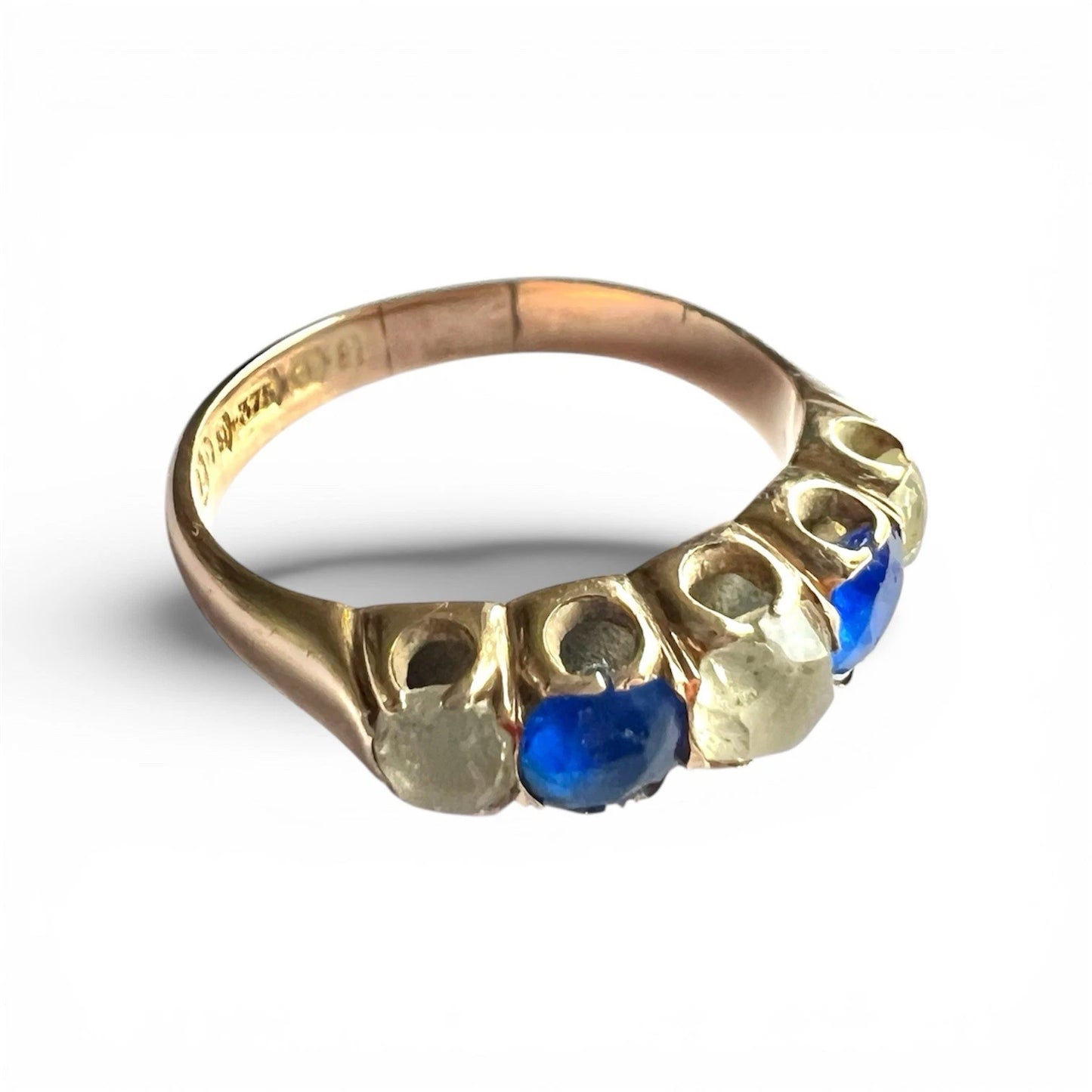 Gold ring with blue and clear gemstones on a white background