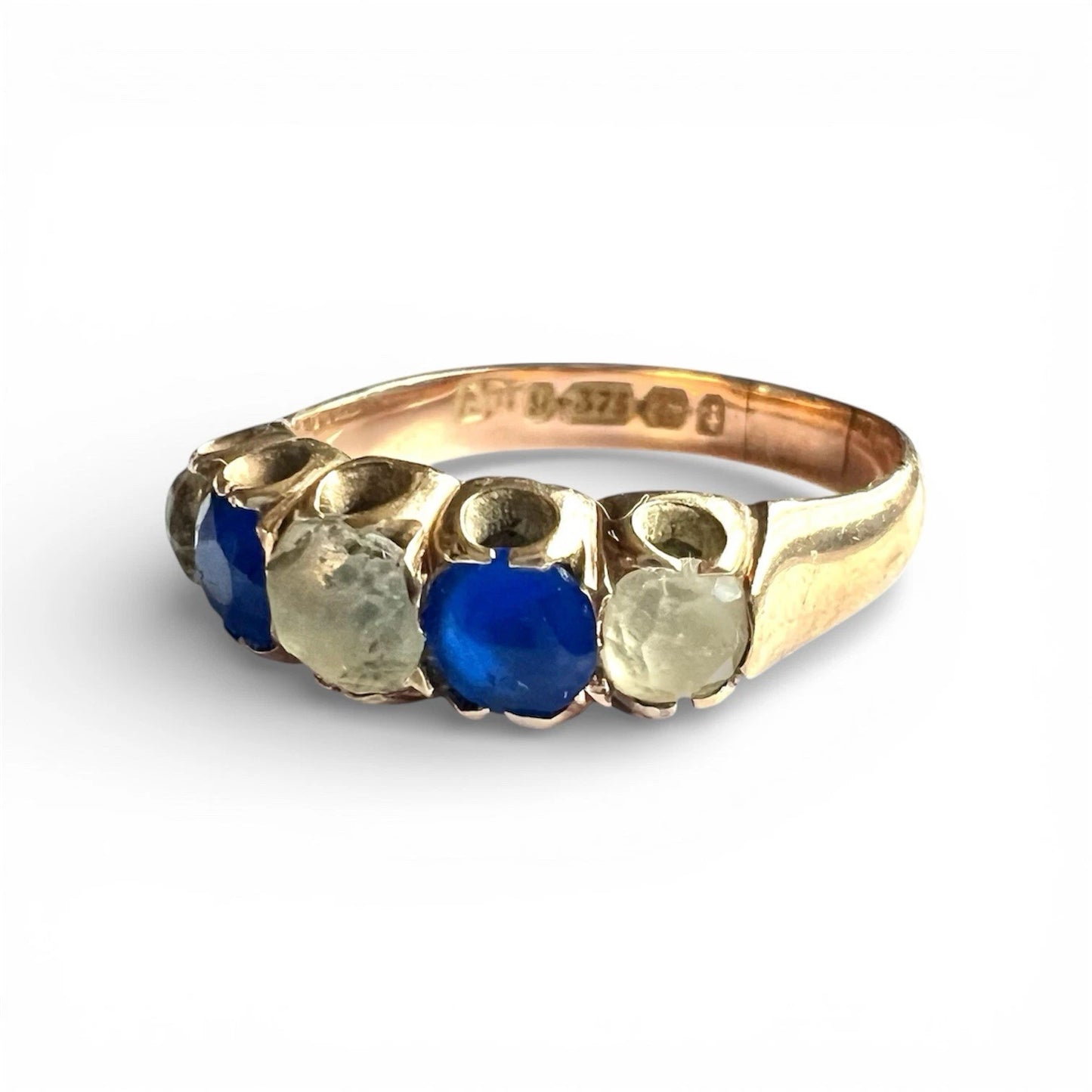 Antique gold ring with blue and clear gemstones on a white background