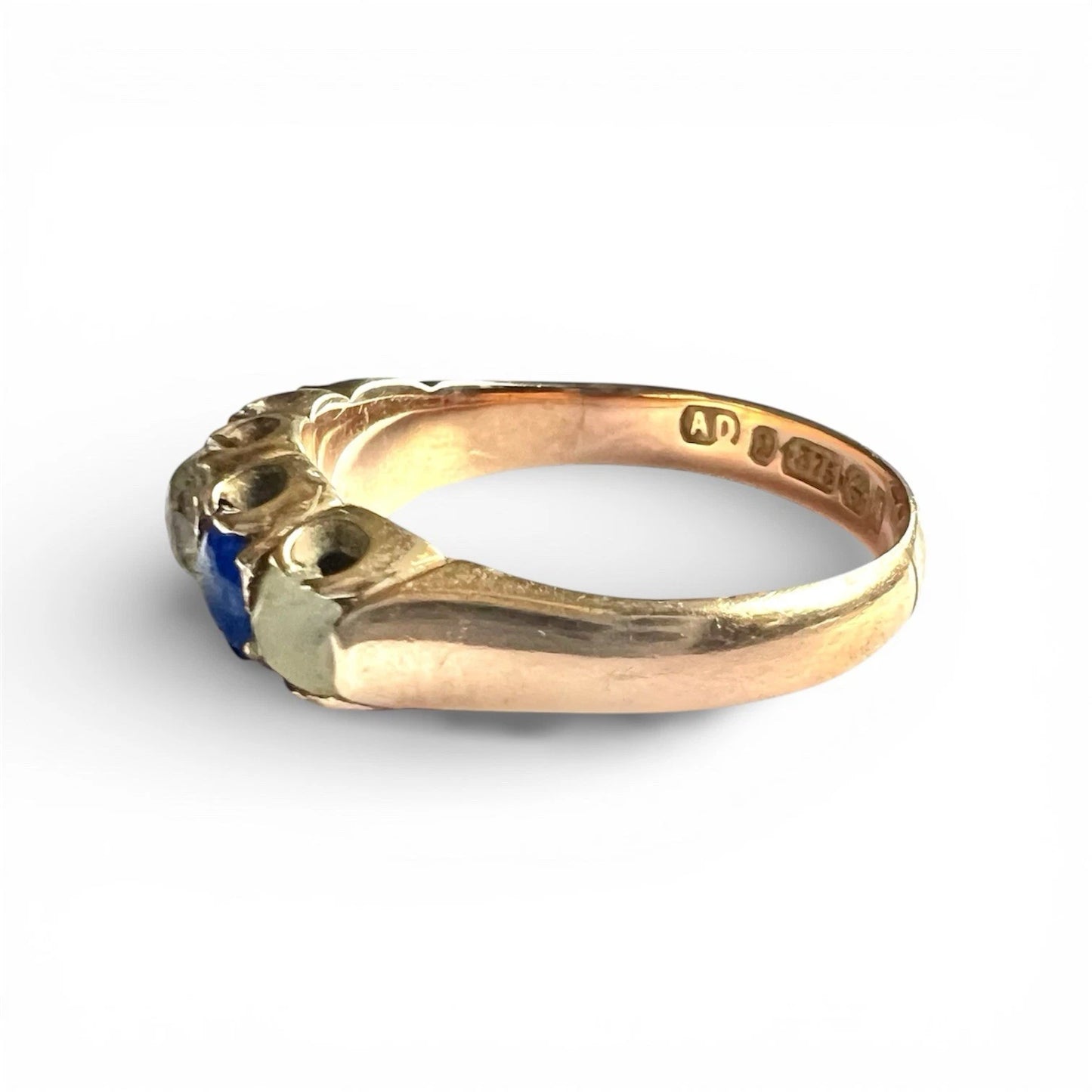 Antique Gold ring with a blue and clear gemstone on a white background, close up side view 