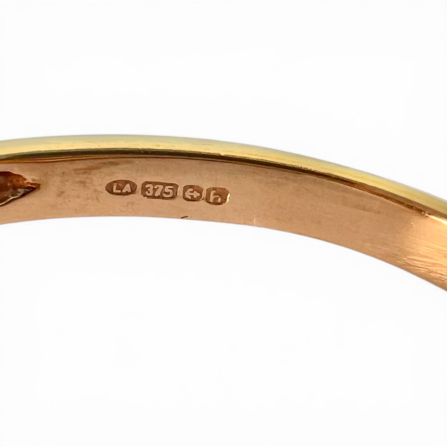 Close-up of a gold ring with full UK hallmarking on a white background