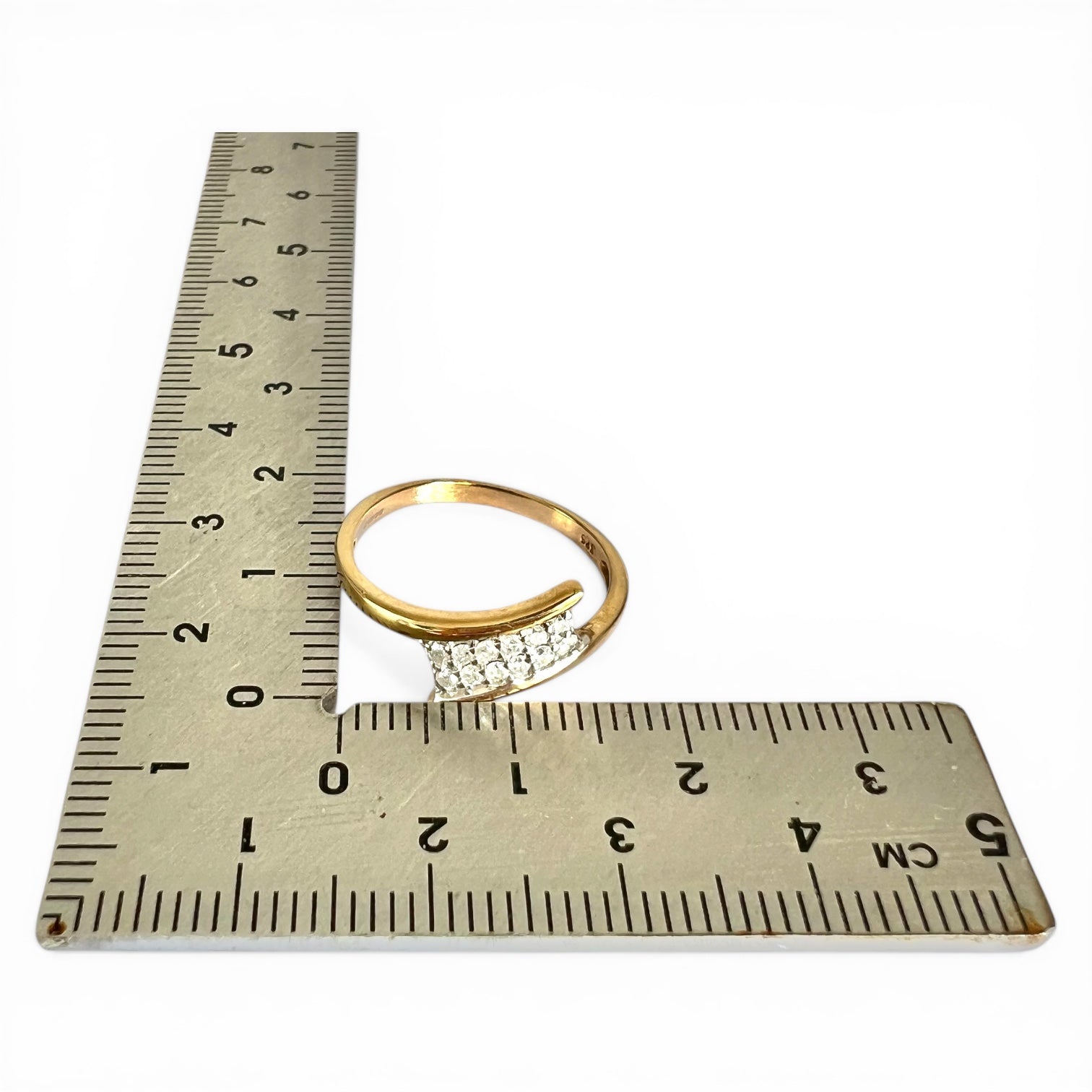 Gold ring with diamonds on a ruler for size reference