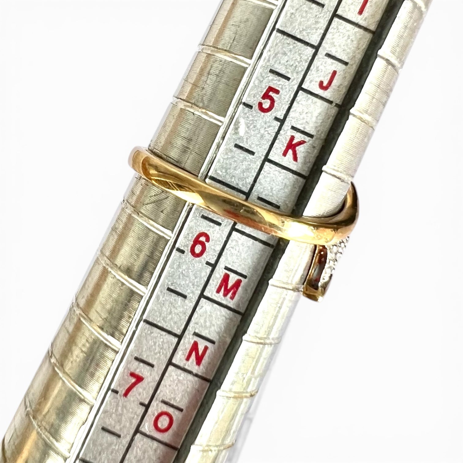 Close-up of a metallic ruler with gold band and red lettering on a white background