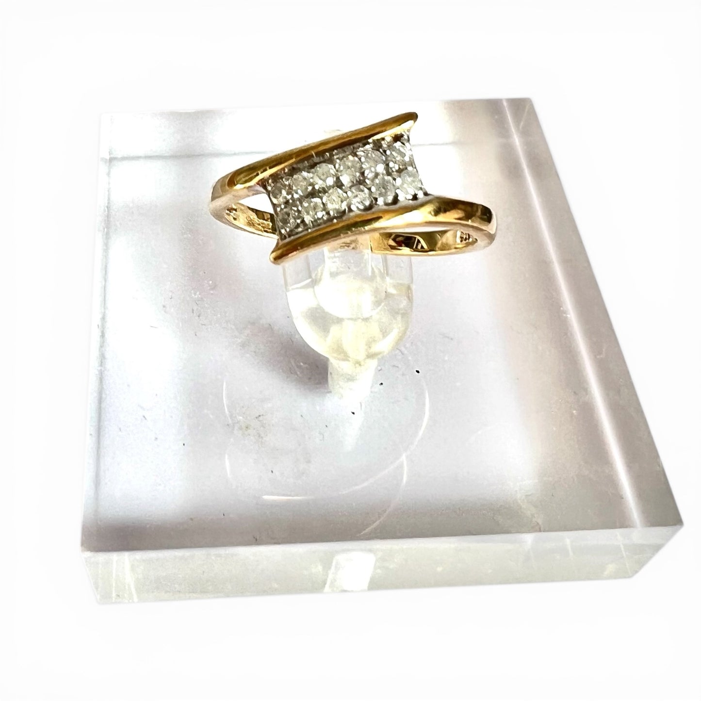 Gold ring with diamond accents on a white stone base