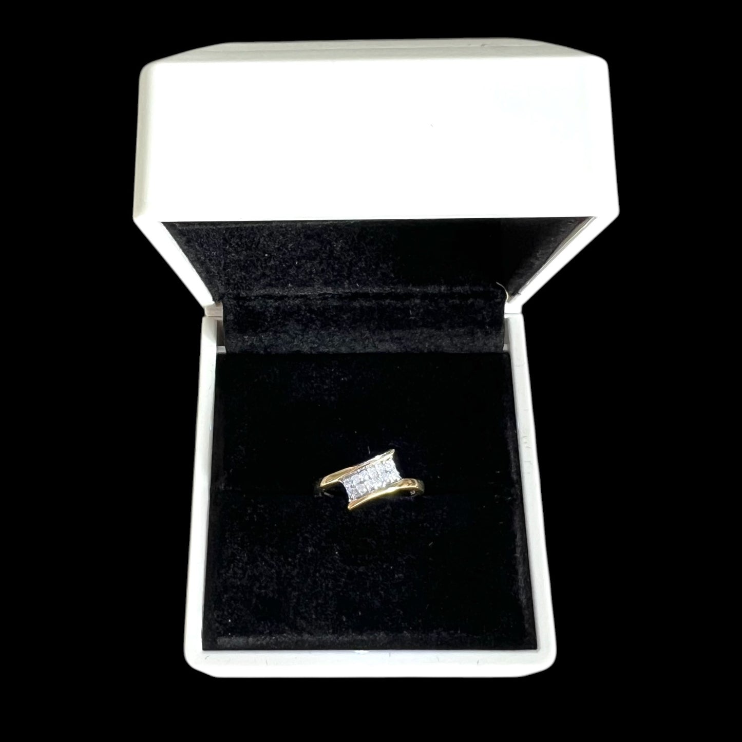 Gold ring with diamonds in a white jewellery box on a black background