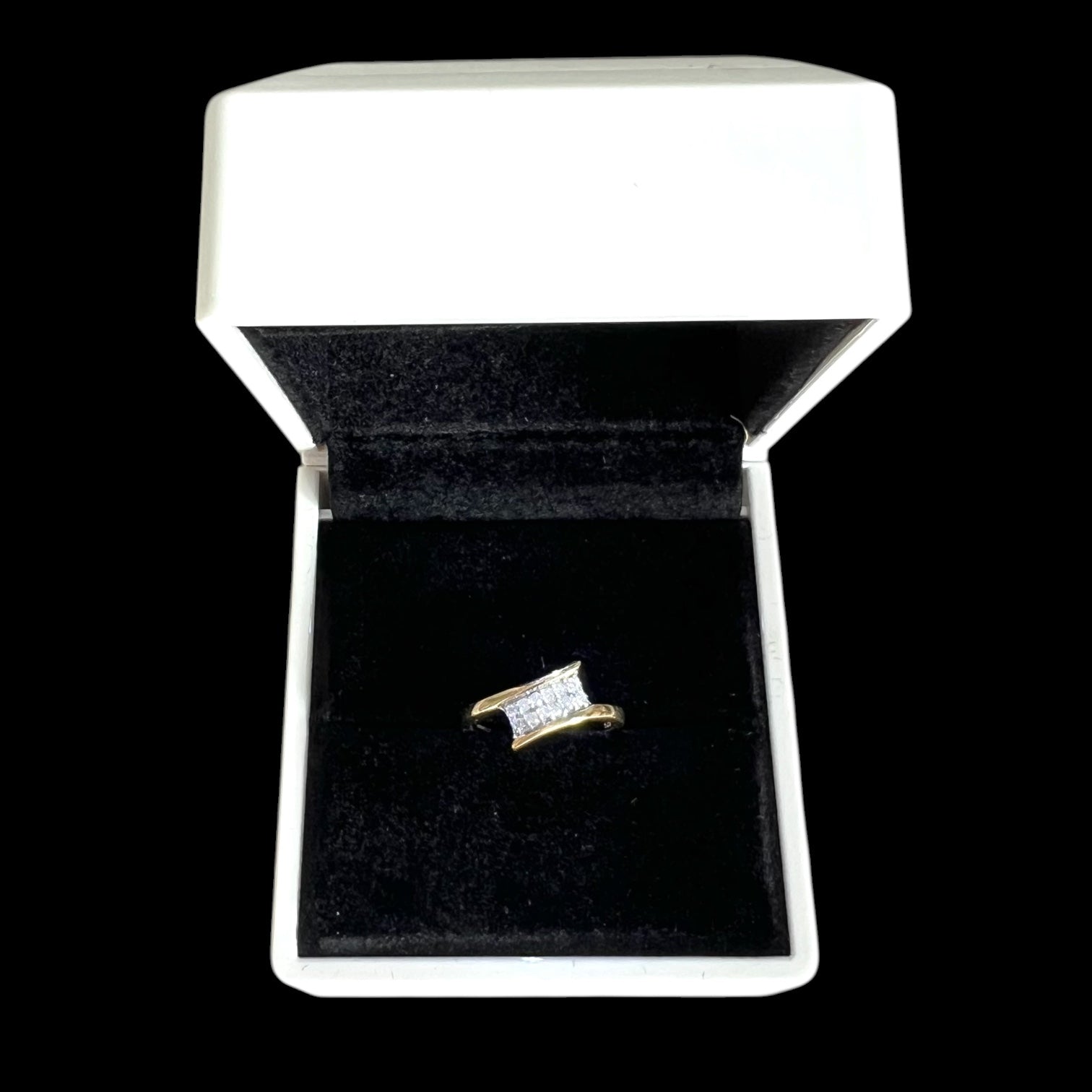 Gold ring with diamonds in a white jewellery box on a black background