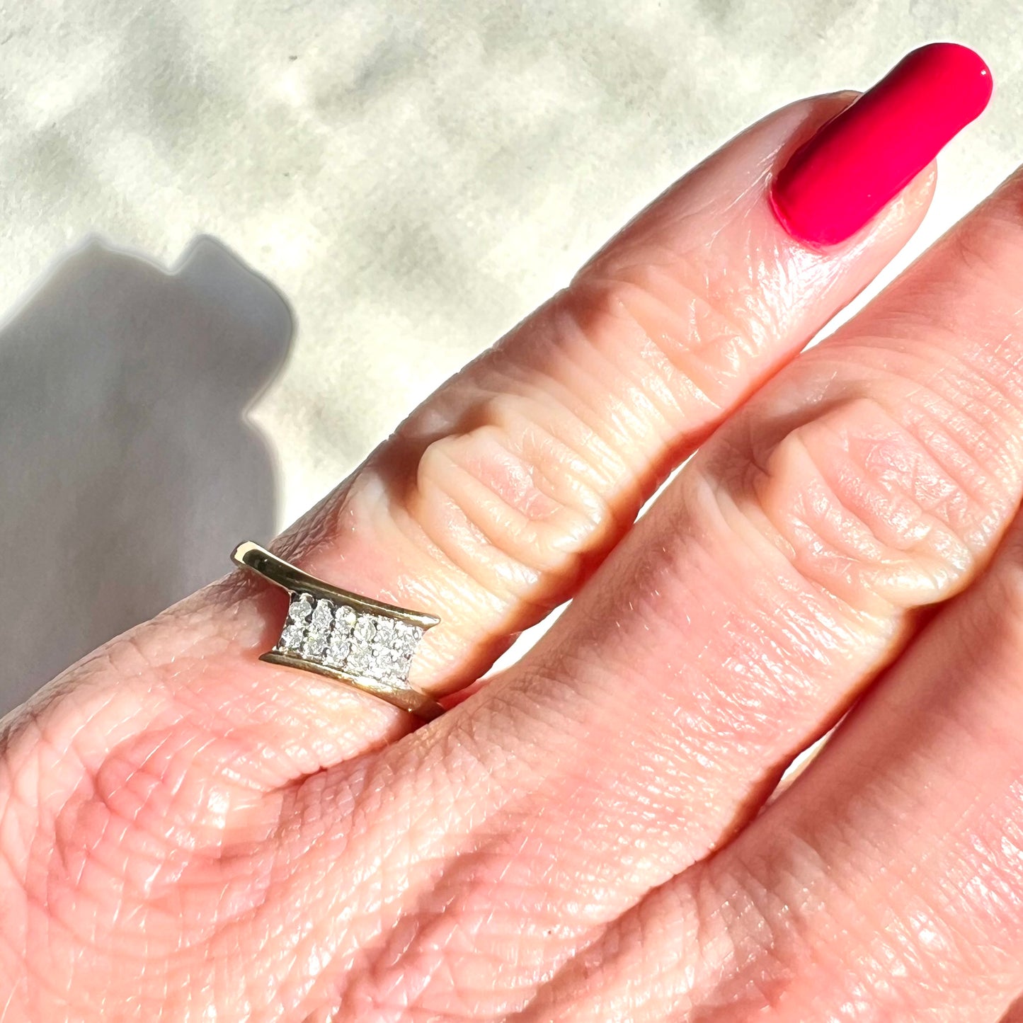 Hand wearing a diamond ring with a textured background