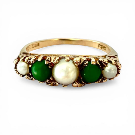 Gold ring with pearls and green stones on a white background