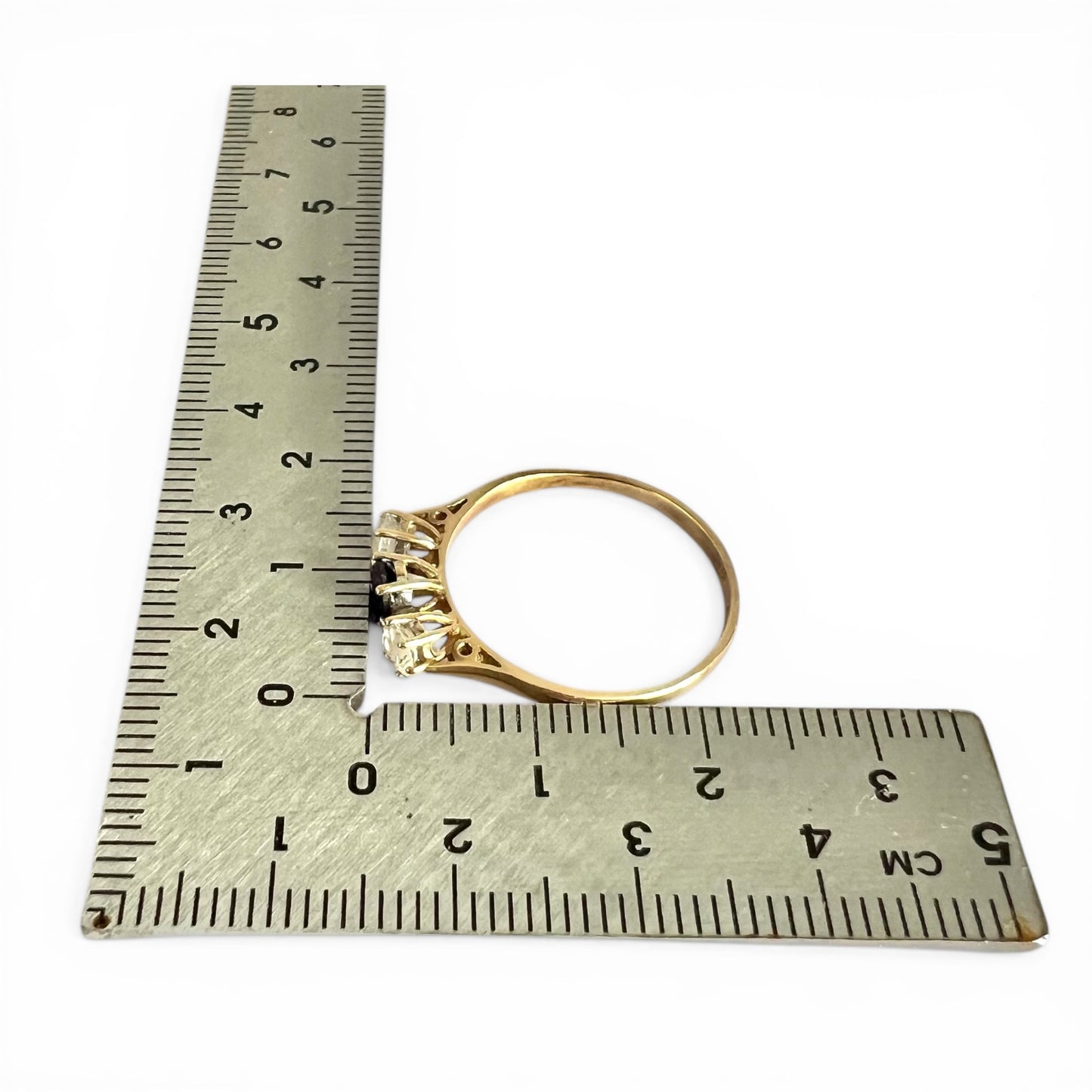 Gold ring next to a ruler on a white background