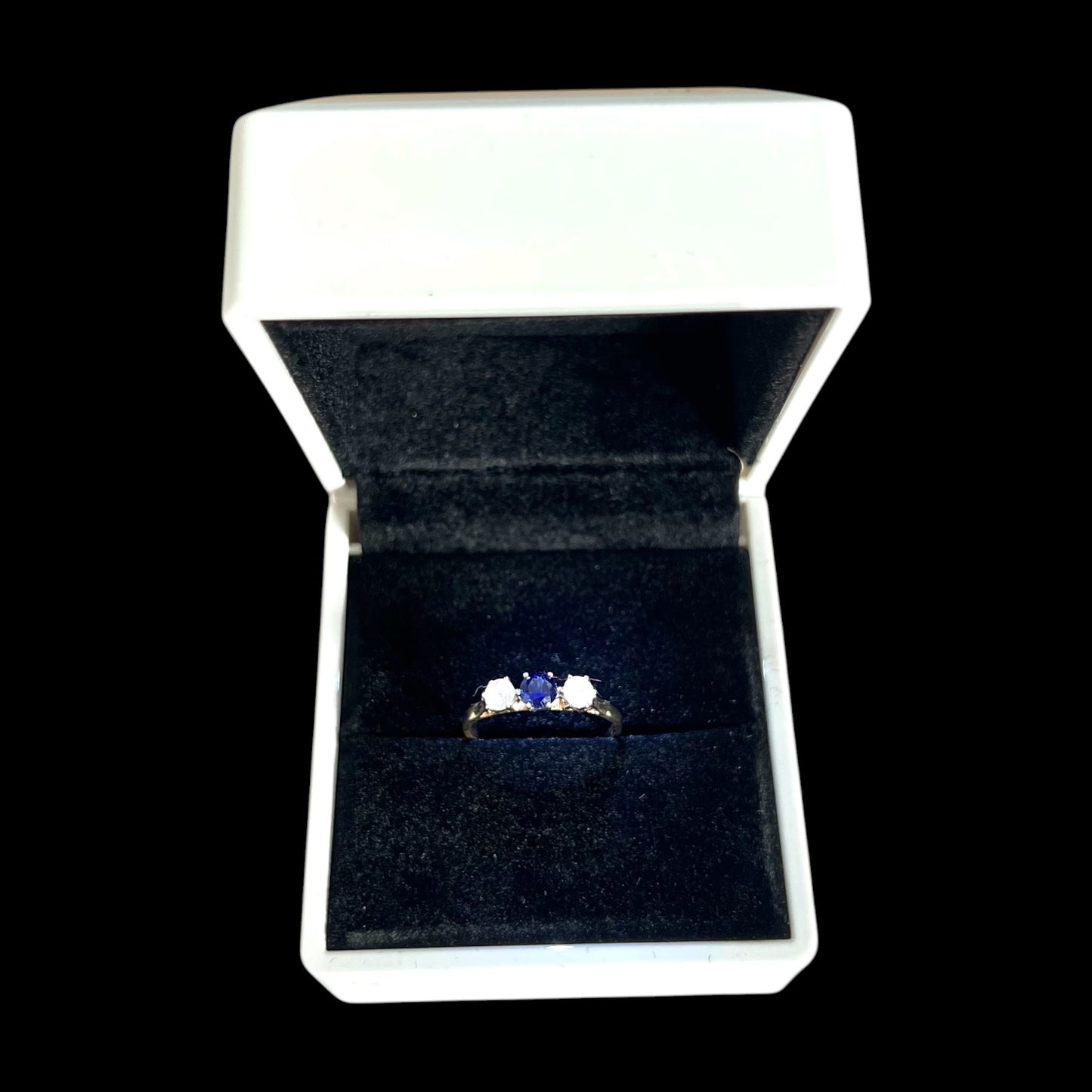 Ring with a blue sapphire gemstone in a white box on a black background