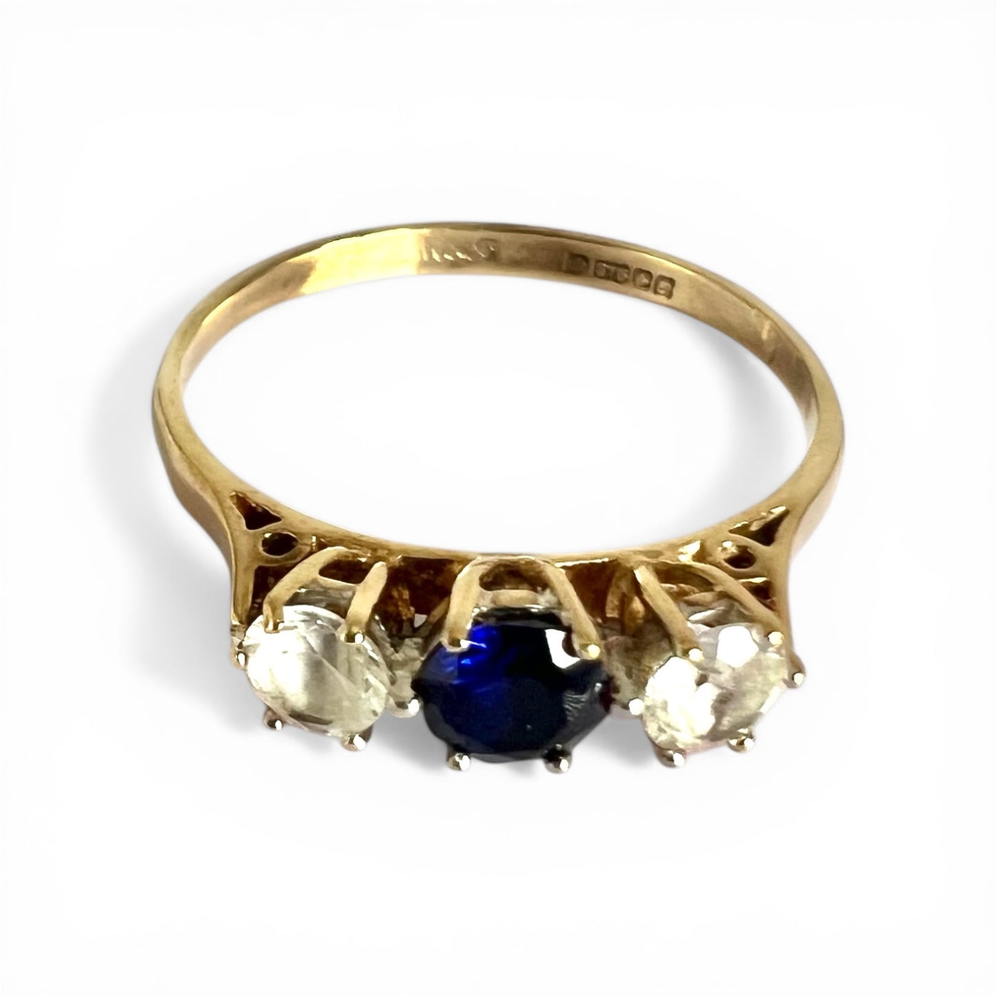 Gold ring with a blue sapphire gemstone on a white background 