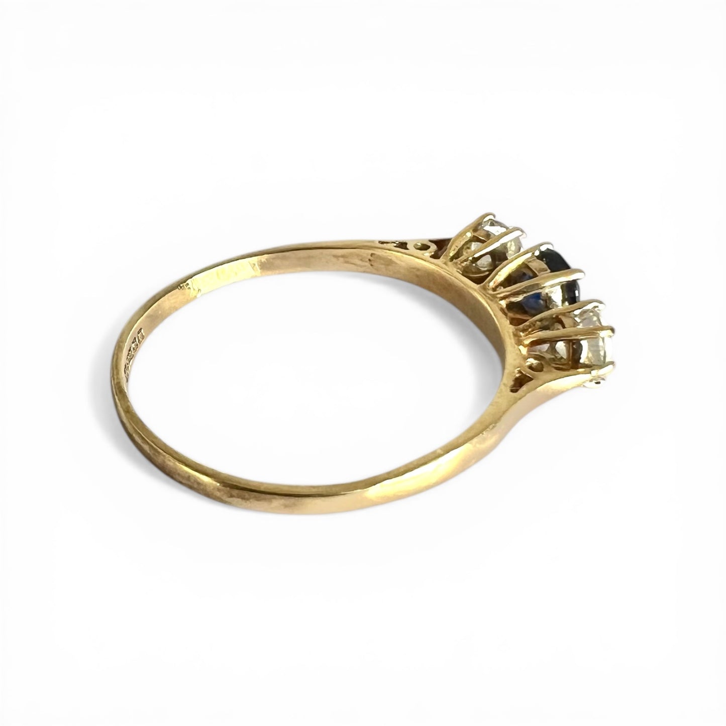 Gold ring with a central gemstone and smaller stones on a white background