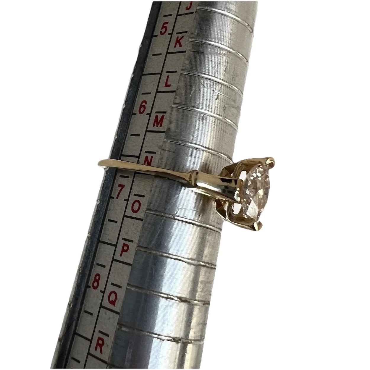 Gold ring with a diamond on a metal ruler for size measurement