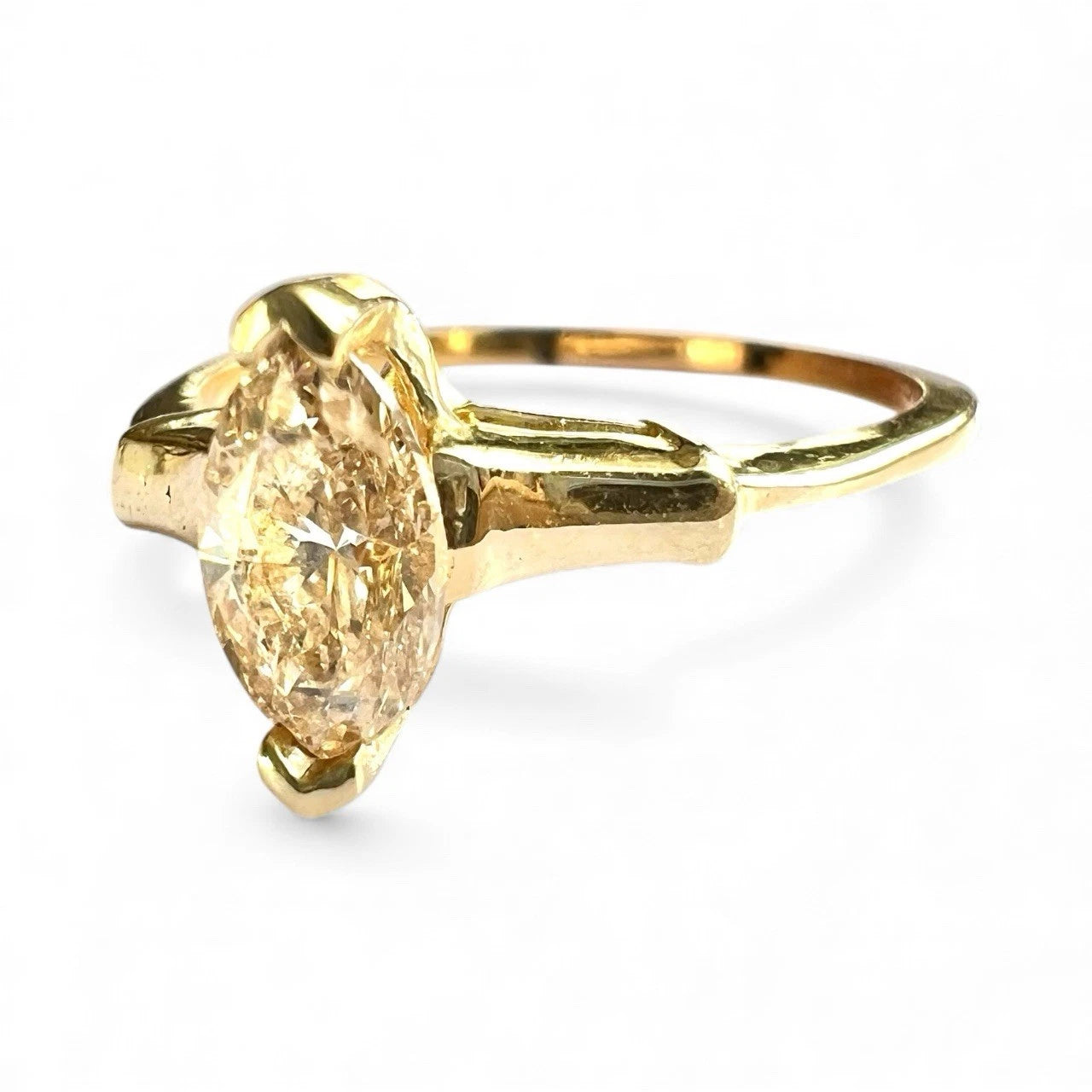 Gold ring with a large marquise-shaped diamond on a white background